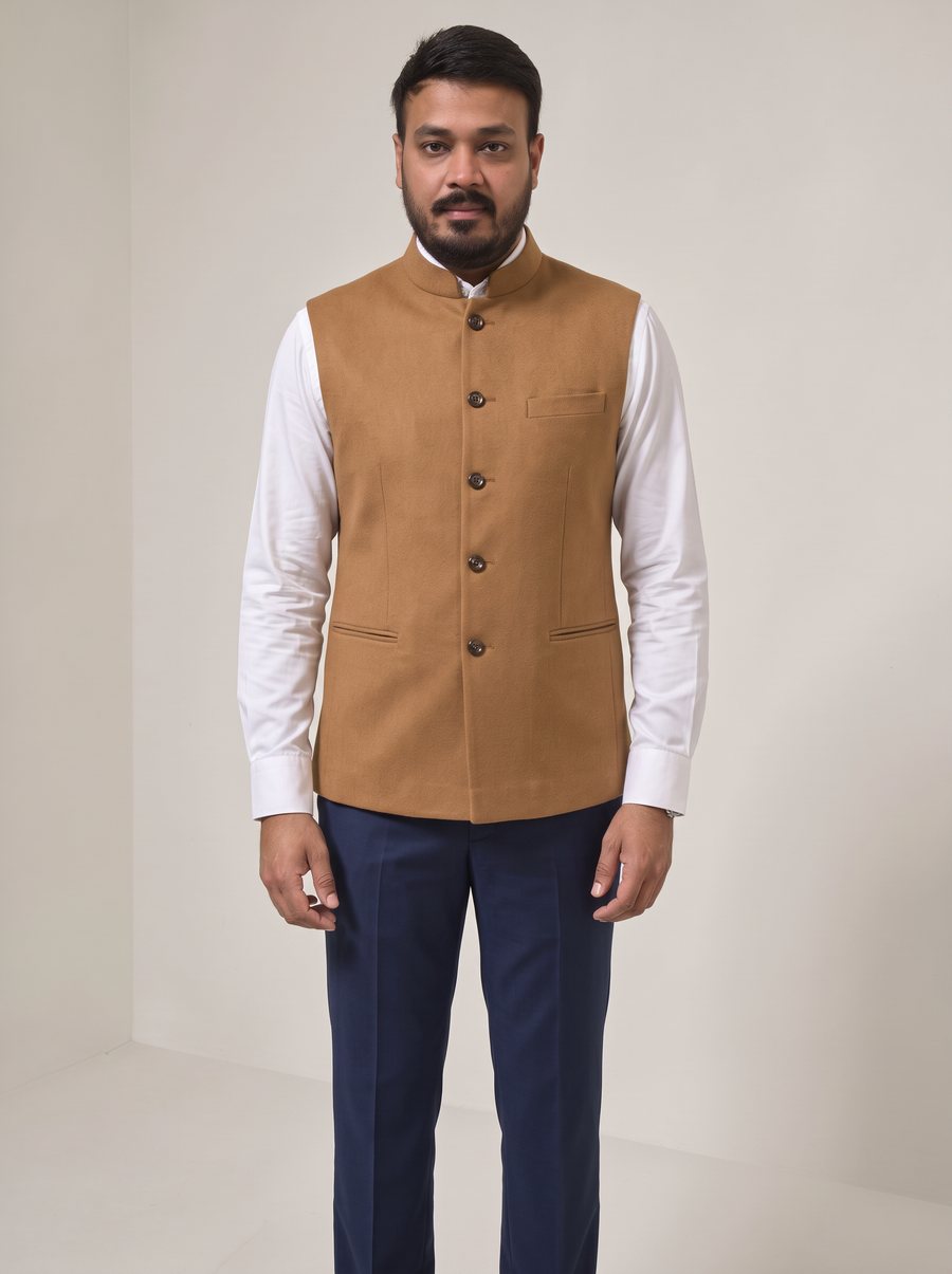 Nitesh Mittal in a sleeveless camel Nehru jacket over a white shirt and navy trousers